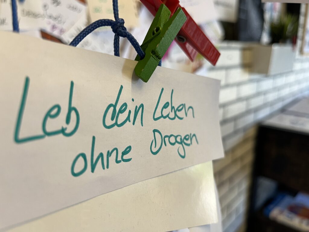 Zettel mit der Aufschrift "Lebe dein Leben ohne Drogen" an einer Pinnwand im Zug